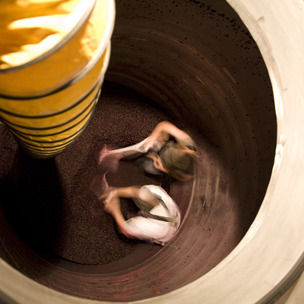 two winery workers inside a wine vat, blurred in motion