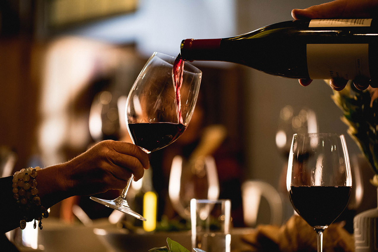 red wine being poured from a bottle into a wine glass