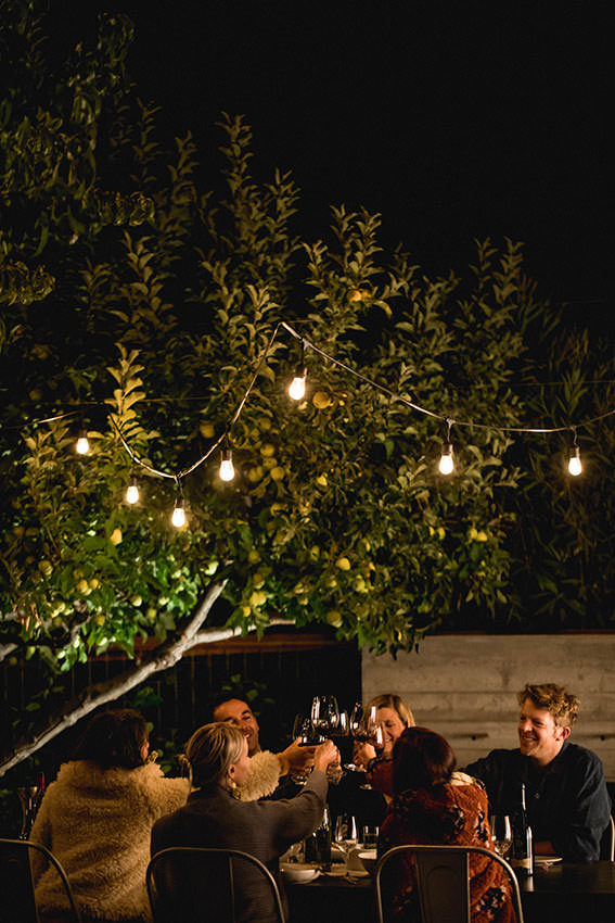 group of friends eating outside and clinking wine glasses