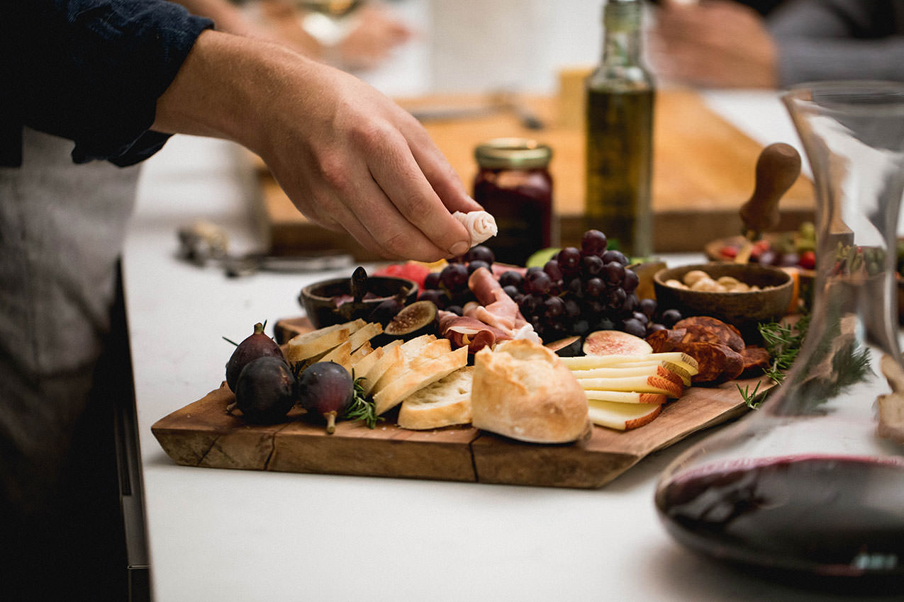 a hand reaching for a charcuterie board on a counter