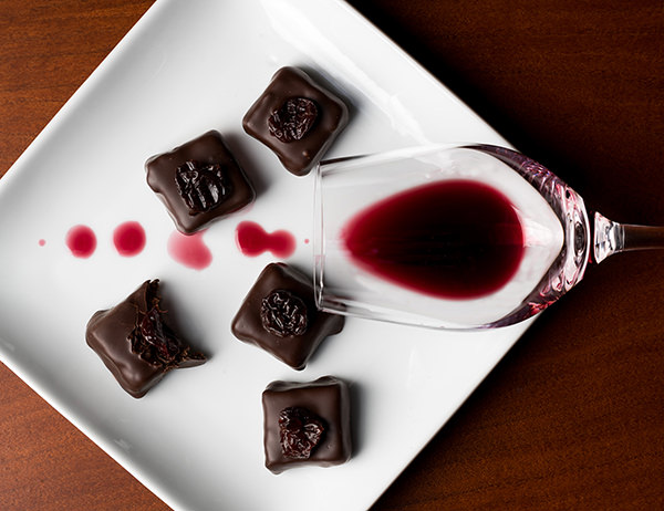 red wine in a glass dribbling over a plate with chocolate truffles