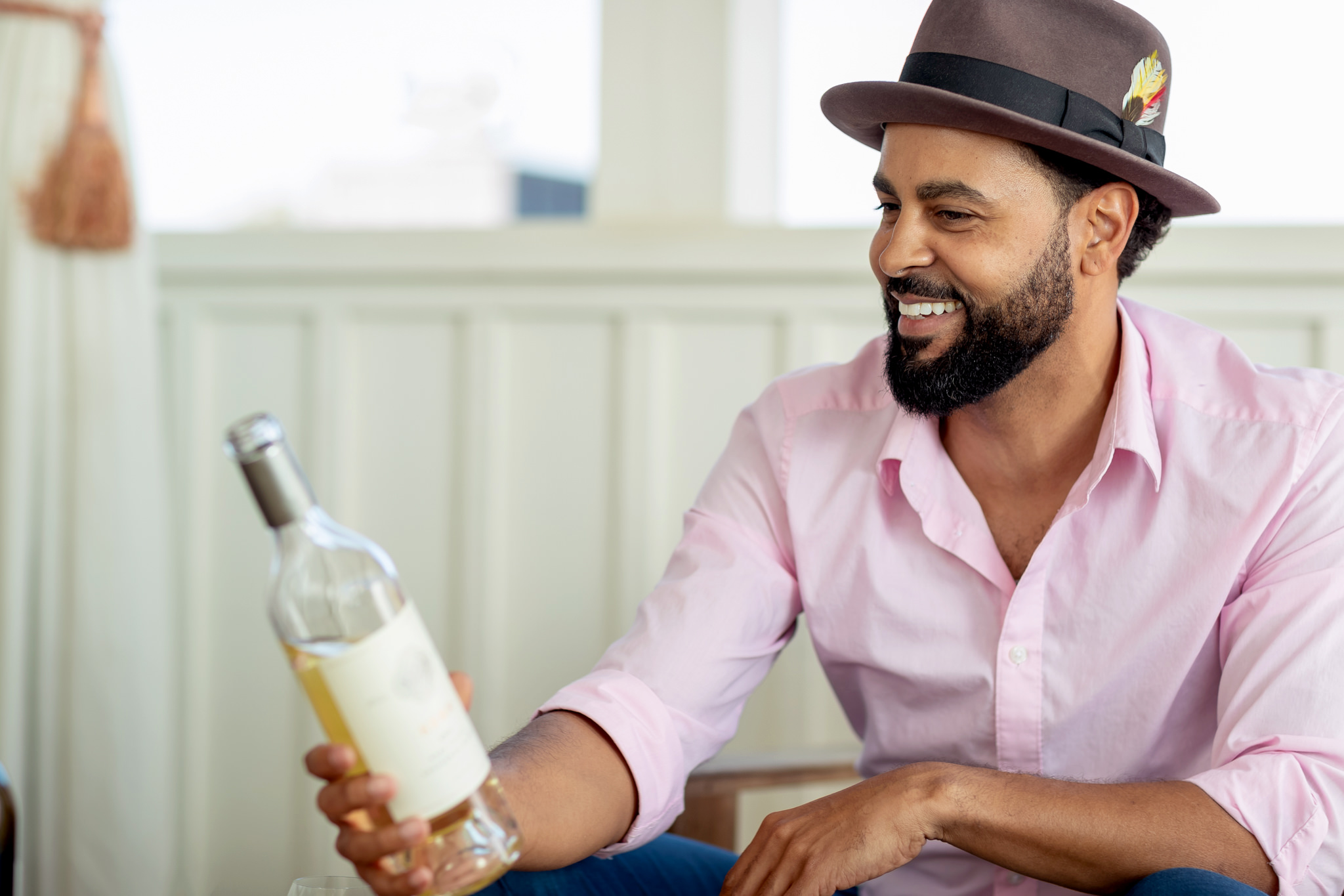 man in hat with white wine in hand