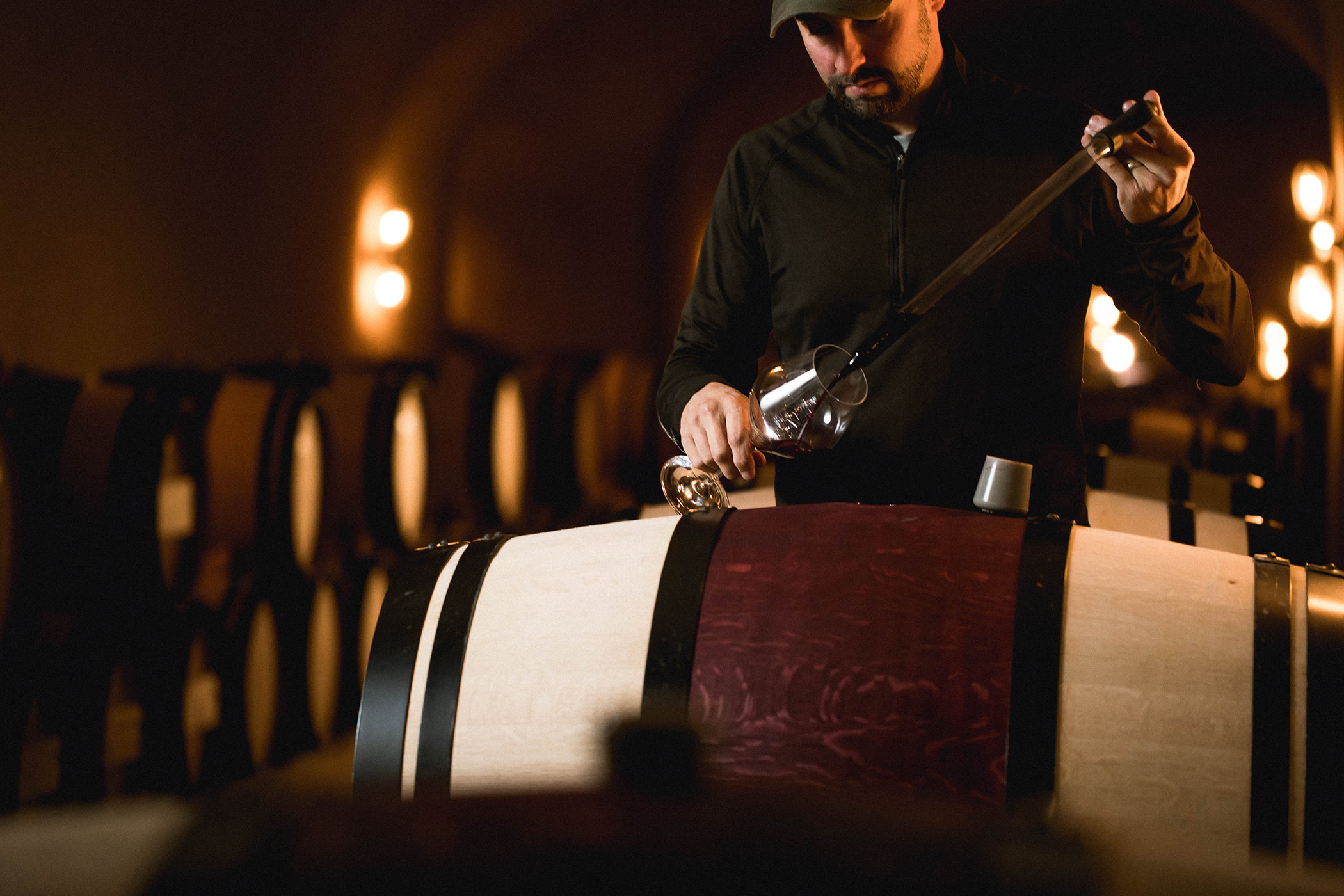winemaker sampling red wine from a barrel