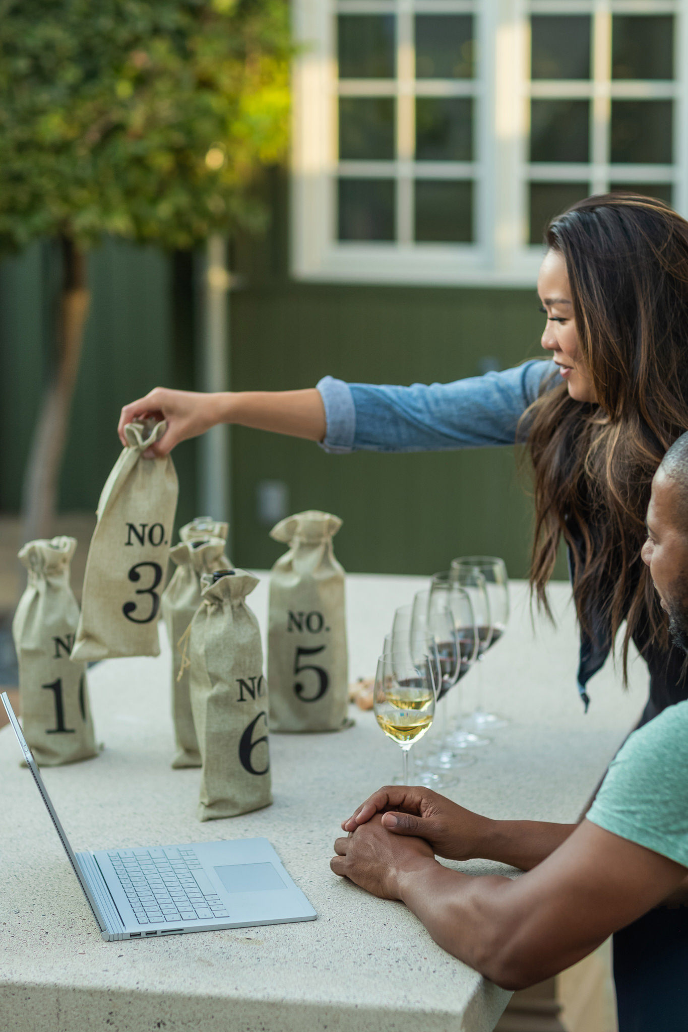 couple at a table with numbered bottles of wine and several tasting glasses lined up