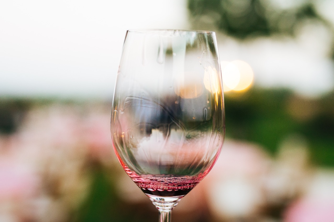 wine glass with a splash of red wine in front of unfocused roses