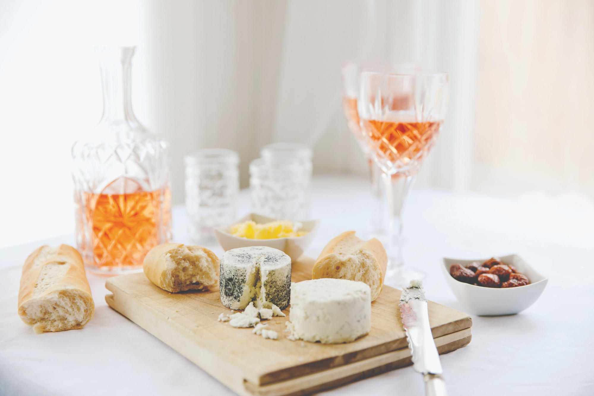 glass of rosé wine sitting on a counter with cheeses